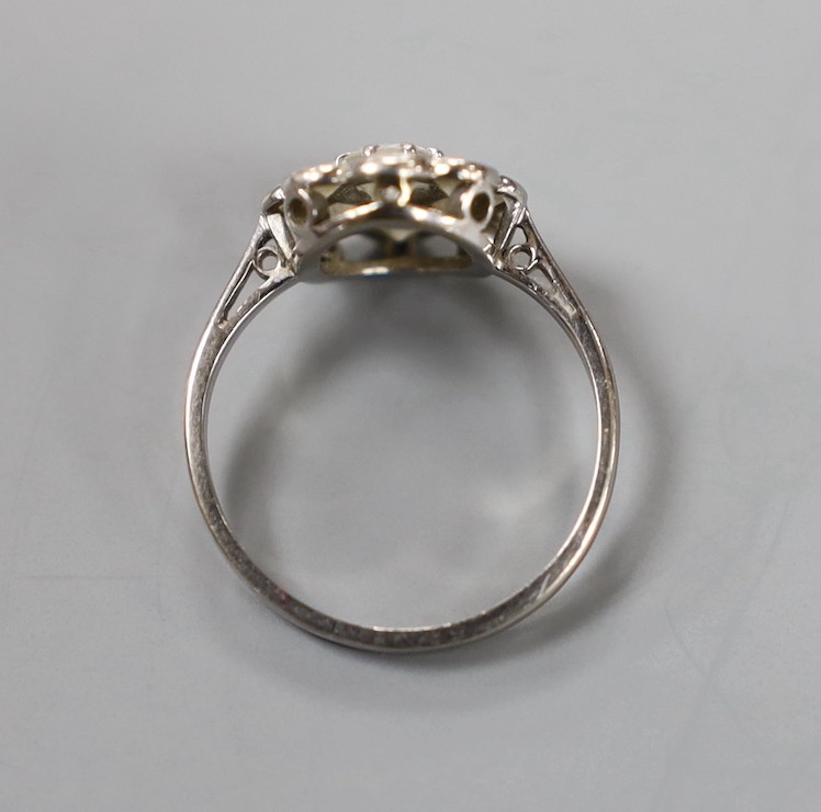 An 18ct, plat and nine stone diamond set flower head cluster ring, size L, gross weight 2.4 grams.